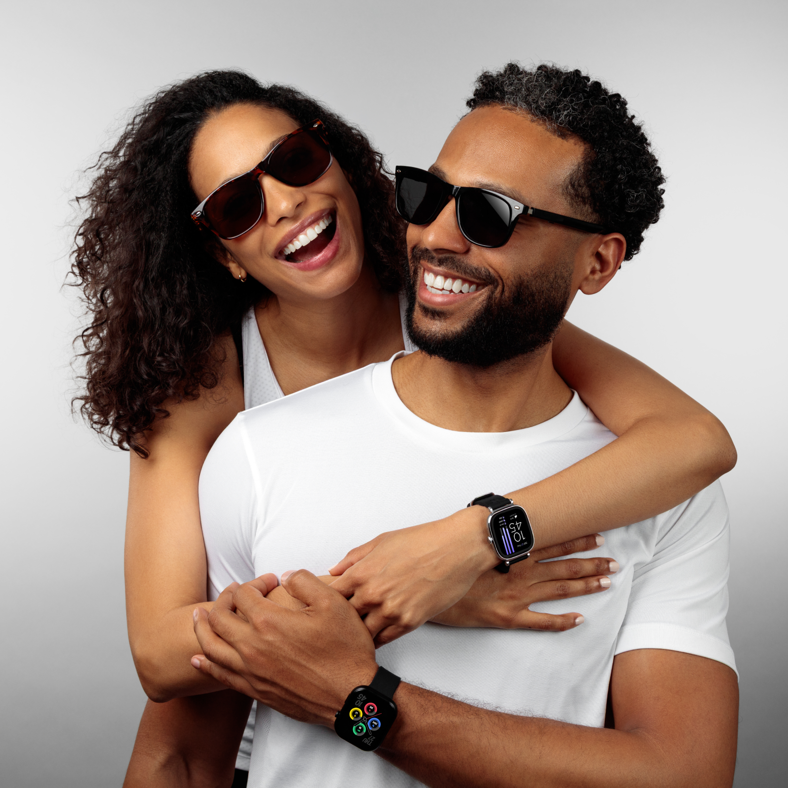 Couple wearing sunglasses and smartwatches against a gray background