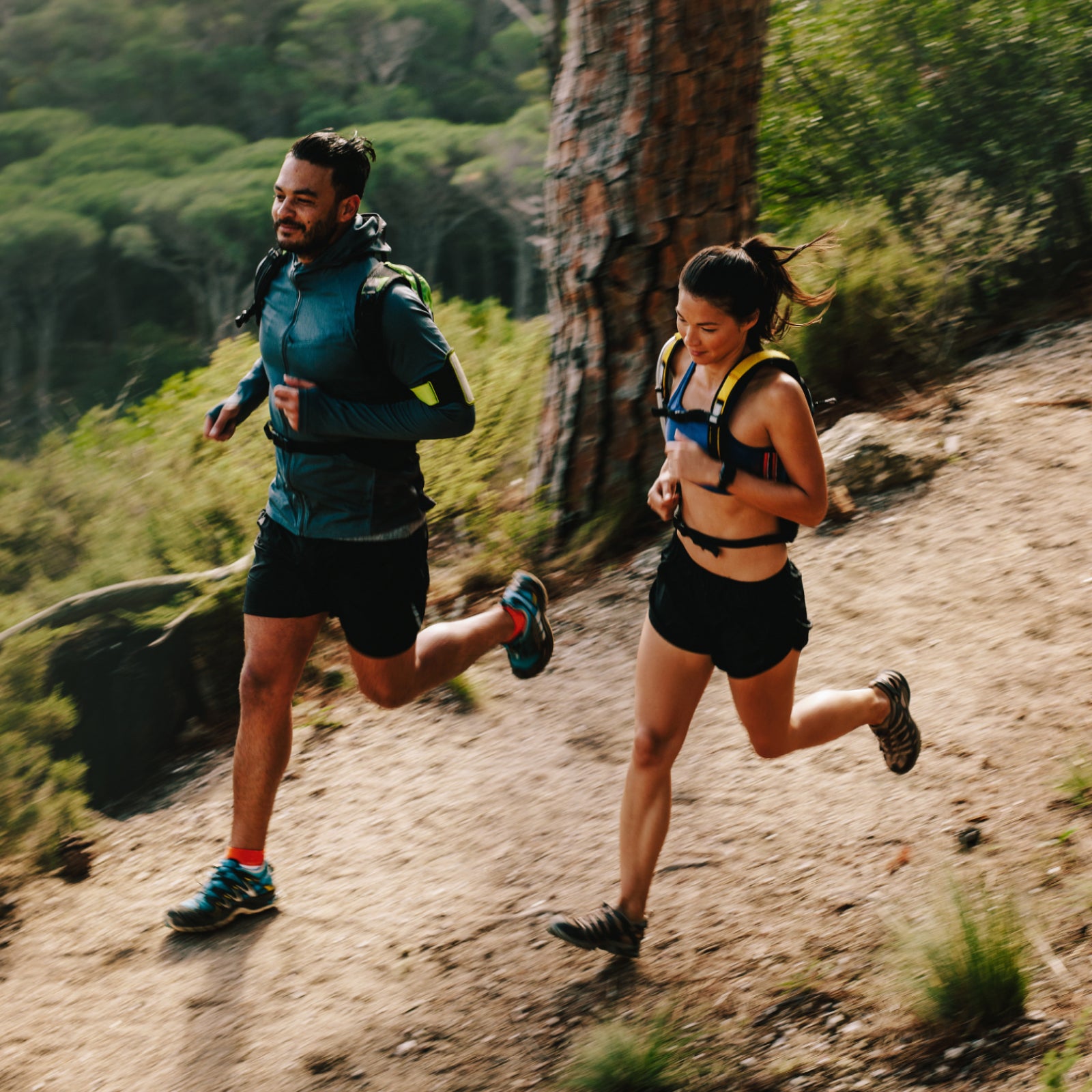 Two runners on a trail in a forested area